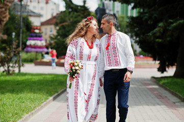 Lovely wedding couple in ukrainian traditional embroidered clothing walk with a bouquet in an old town.