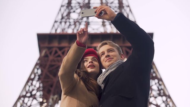 Happy loving couple of tourists doing selfie on background of Eiffel Tower