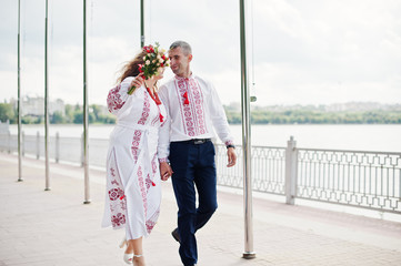 Fabulous wedding couple in traditional clothing walking along the lakeside.