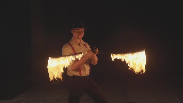 Male artist performing fire show at dark in slow motion.