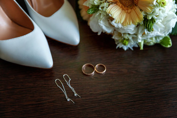 wedding accessories. bridal shoes, bouquet, earrings and rings on wooden background