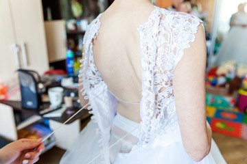 Naklejka premium Bridesmaid helping bride with her wedding dress. Wedding details