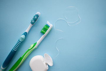 Two toothbrushes and dental floss on blue background - obrazy, fototapety, plakaty