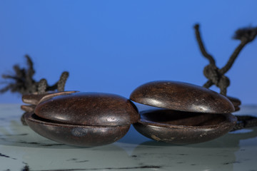 Two wooden spanish castanets in front of blue background