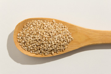 Sesamo. Nutritious grains on a wooden spoon on white background.