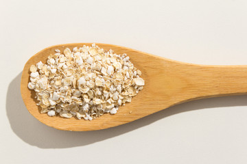 Oat cereal grain. Nutritious grains on a wooden spoon on white background.
