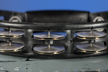 A black tambourine in front of blue background
