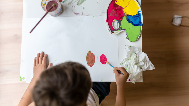 Young boy painting on paper with colorful paints