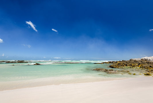 Beach view with white sand, rocks and crystal clear water at Brandfontein - Rietfontein Nature Reserve near Cape Agulhas, Western Cape Province, South Africa.