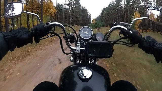 Biker rides along the forest road on the motorcycle chopper slow motion