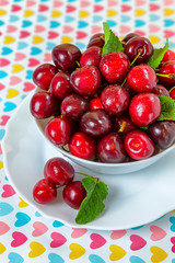 Cherries in a white plate on the table.