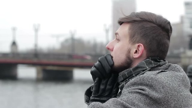 A sad young man with problems on a bridge by the river