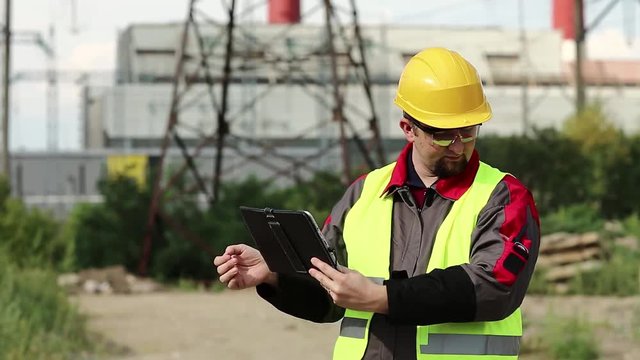 Power engineering specialist with personal computer at heat electric power station. Worker at heat electric power station with tablet computer talks via portable radio transmitter