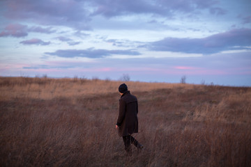 Man walking in the autumn field during sunset