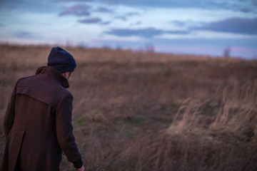Man walking in the autumn field during sunset