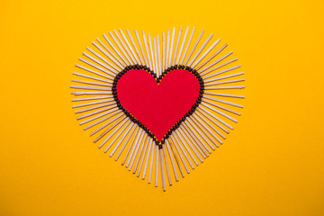 Heart shape of love from matches on a yellow background. Romantic symbol. Love concept