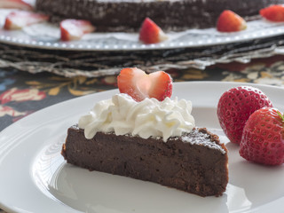 Piece of chocolate tort topped with heartshaped strawberry