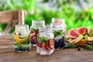 Fototapeta na wymiar Mason jars of infused water with fruits and berries on wooden table