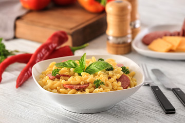 Pasta with sausage in ceramic bowl on kitchen table