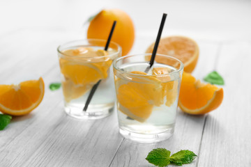 Glasses of delicious cocktails with orange on table