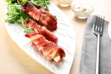 Plate with bacon wrapped chicken nuggets on table