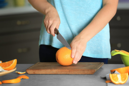 Woman cutting orange on board in kitchen