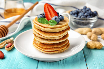 Plate with buckwheat pancakes and berries on wooden table