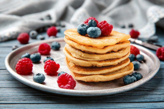 Metal dish with buckwheat pancakes and berries on table