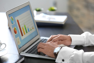 Marketing manager using laptop at table in office