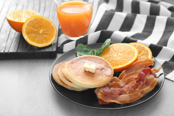 Tasty breakfast with pancakes, bacon and sliced orange on plate