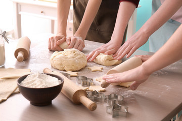 Obraz na płótnie Canvas Women preparing puff pastry at table in kitchen