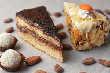 Pieces of tasty cakes and candies on grey background