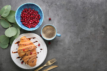 Fresh yummy croissant with cranberry and cup of coffee served for breakfast on grey background