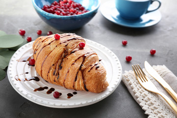 Plate with fresh yummy croissant on table
