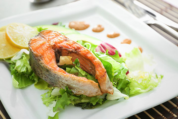 Delicious fried rainbow trout with salad and sauce on plate, closeup
