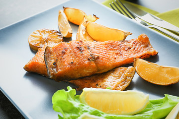 Delicious fried rainbow trout with lemon on plate, closeup
