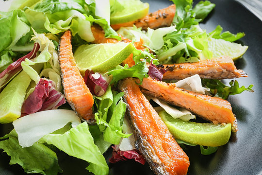 Delicious salad with fried rainbow trout on plate, closeup