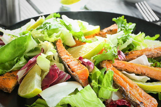 Delicious salad with fried rainbow trout on plate, closeup