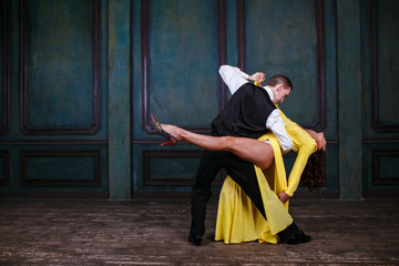 Young pretty woman in yellow dress and man dance tango