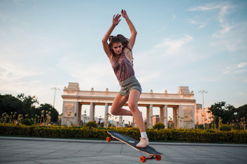Young sporty woman riding on the longboard in the park