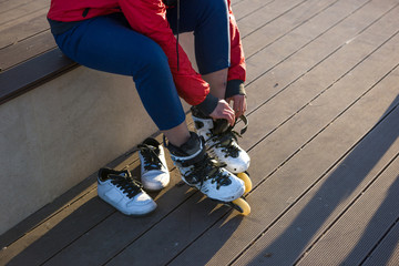 Woman skating in park. Girl putting on inline skates. Asian Chinese woman in outdoor activities.