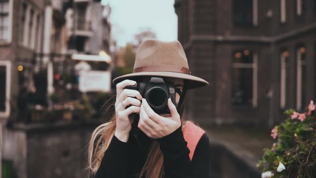 Portrait of happy Caucasian woman with a camera. Attractive cheerful lady in stylish hat taking a picture 4K front view.
