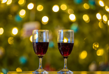 Two wine glass half full with red wine kept in front of Christmas tree