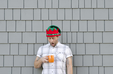 Man with a Christmas hat, shocked by an empty coffee mug.