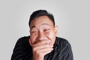Funny Asian man smiling shy close his mouth