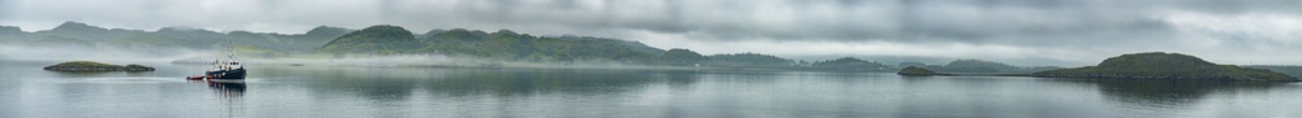 Alone boat driving through in the foggy sea in the scottish highlands