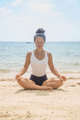 young attractive woman meditating on beach
