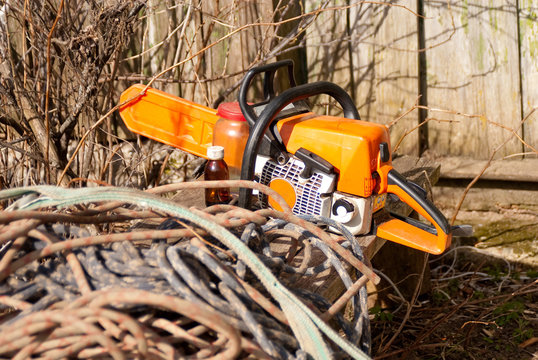 Chainsaw lies on rural bench with coils of ropes