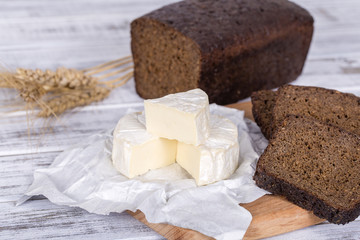 Brie type of cheese. Camembert cheese. Fresh Brie cheese and a slice on a wooden board with black bread. Italian, French cheese