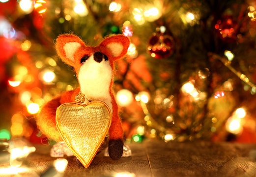 Fox toy. Love heart. New years greetings background. Fancy handmade toy from wool on bokeh Christmas background. Copyspace for congratulations.